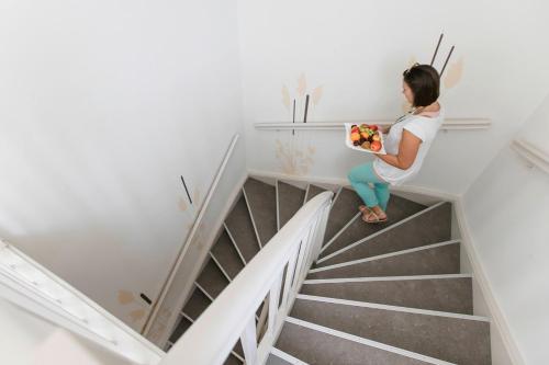 a woman sitting on the stairs holding a bowl of fruit at R&R Residenzen Ferienwohnungen in Mitterbach