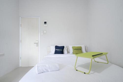 biała sypialnia z łóżkiem i zielonym stołem w obiekcie Urbanview Hotel Bari Syariah Palembang By RedDoorz w mieście Sukarami