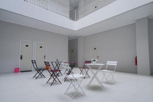 a group of chairs and tables in a white room at Urbanview Hotel Bari Syariah Palembang By RedDoorz in Sukarami