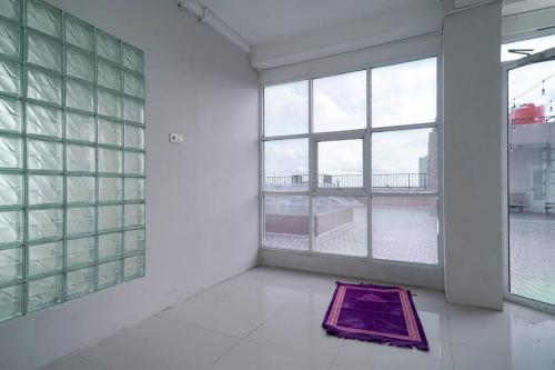 a room with windows and a purple rug on the floor at Urbanview Hotel Bari Syariah Palembang By RedDoorz in Sukarami