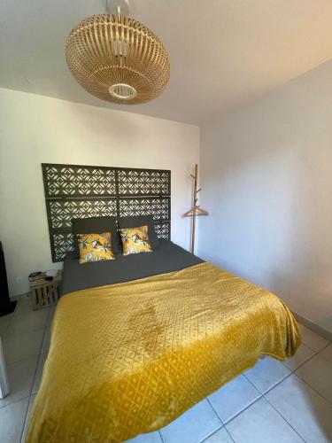 une chambre avec un grand lit avec une couverture jaune dans l'établissement Le Patio, coeur de ville avec garage et jardin, à Vannes