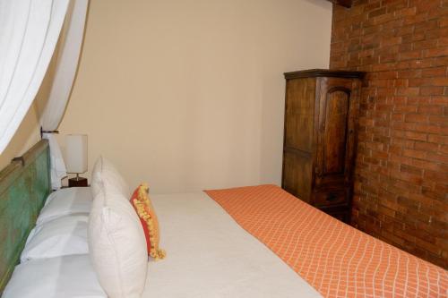 a bedroom with a bed and a brick wall at Hostal Donde Regina in Guatemala