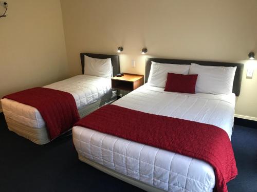 a hotel room with two beds with red sheets at The Peaks Motor Inn in Ohakune