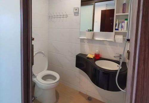 a bathroom with a toilet and a sink at Cozy Studio @Skyhouse BSD in Samporo