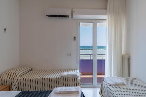 two beds in a room with a view of the ocean at Beach Suite Hotel in Bellaria-Igea Marina