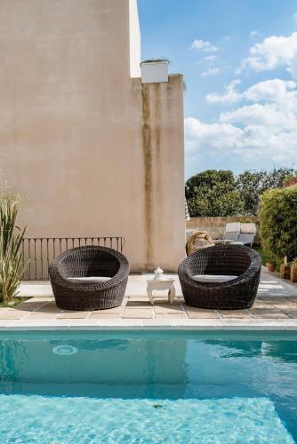 two wicker chairs are next to a swimming pool at Wp Relais apartments in Diso