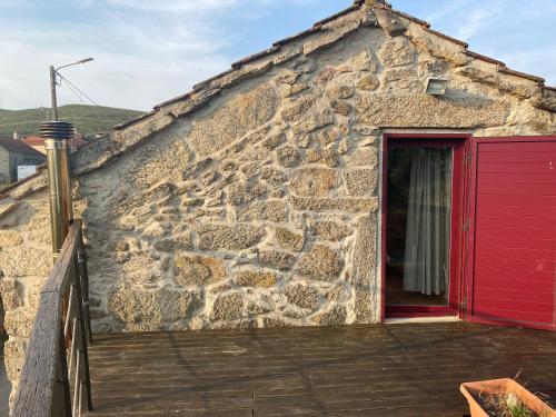 a red door on a stone building with a wooden deck at Casa do Curral in Negrões