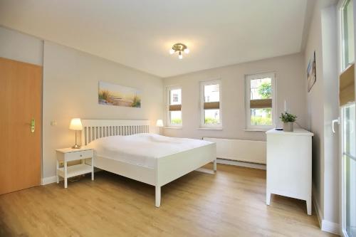 a white bedroom with a bed and two windows at Strandvilla Krabbe Wohnung 15 in Boltenhagen