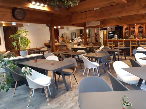 an empty restaurant with tables and white chairs at Hotel et Spa Le Lion d'Or in Pont-lʼÉvêque