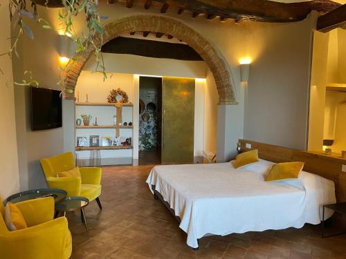 a bedroom with a bed and two chairs and a television at La Corte Segreta in Montepulciano