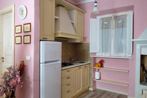 una cucina con pareti rosa e frigorifero bianco di Casa Sofia sul Lago Trasimeno a Torricella
