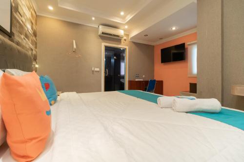 a bedroom with a large white bed with an orange wall at Sans Hotel Beauty Palembang in Sukarami