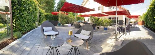 un patio con sillas, mesas y sombrillas rojas en Das SinGold Hotel mit Highspeed WLAN und digitalem Schlüssel, en Schwabmünchen