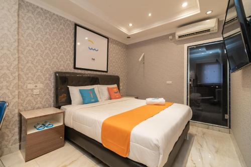a bedroom with a large bed and a tv at Sans Hotel Beauty Palembang in Sukarami