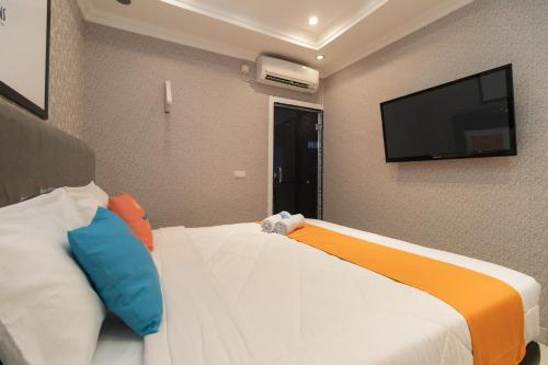 a bedroom with two beds and a flat screen tv at Sans Hotel Beauty Palembang in Sukarami