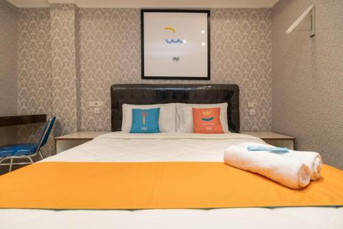 a bedroom with a bed with orange and blue pillows at Sans Hotel Beauty Palembang in Sukarami