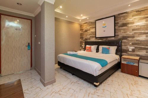 a bedroom with a large bed and a brick wall at Sans Hotel Beauty Palembang in Sukarami