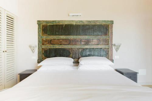 a bedroom with a large white bed with a wooden headboard at Wp Relais apartments in Diso