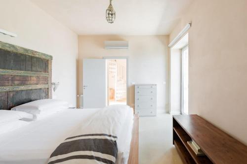 a white bedroom with a bed and a wooden dresser at Wp Relais apartments in Diso