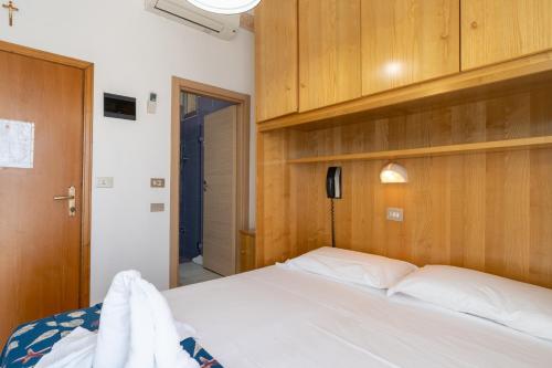 a bedroom with a white bed and wooden cabinets at Hotel Milanese in Rimini