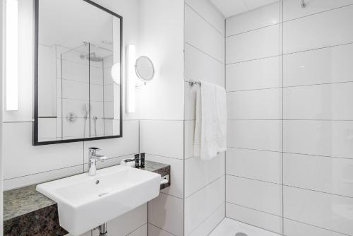 a white bathroom with a sink and a mirror at Bilderberg Parkhotel Rotterdam in Rotterdam