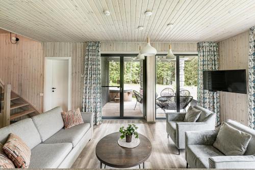 a living room with a couch and a table at Evita - 'Virš Ąžuolų' - Forest SPA - Horses - Lake in Paplatelė