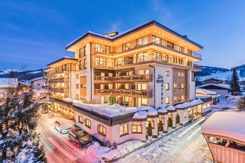 un edificio de apartamentos con nieve en el suelo en Hotel Zentral ****superior, en Kirchberg in Tirol