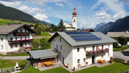a house with solar panels on the roof with a church at Marhof Pustertal in Anras