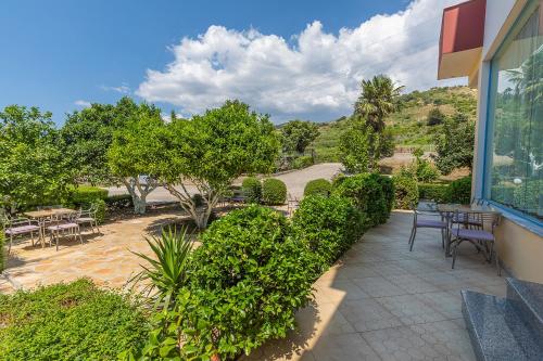 an outdoor patio with tables and chairs and trees at Hotel Dini in Vlorë
