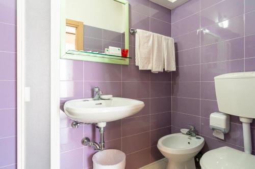 a purple bathroom with a sink and a toilet at Hotel Milanese in Rimini