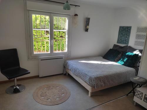 a bedroom with a bed and a window and a chair at L'Annexe in Saint-Martin-de-Valgalgues