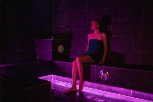a woman sitting in a purple room with a laptop at Hotel Schopfenhof in San Candido