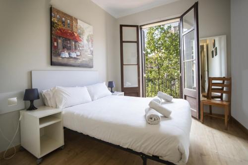 a bedroom with a large white bed and a window at 23PAR1007 Comfortable apartment in Paralel in Barcelona