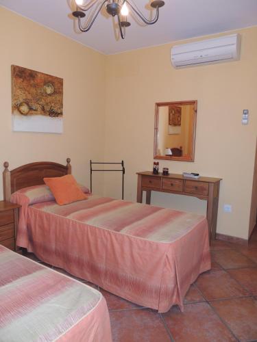 a bedroom with two beds and a table and a mirror at Casa La Mercedes in Ballobar