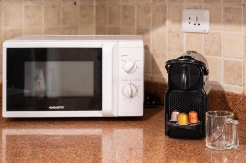 a microwave sitting on a counter next to a coffee maker at Distinct & Decent 2 BDR Apt Steps From Nightlife and Airport in Cairo