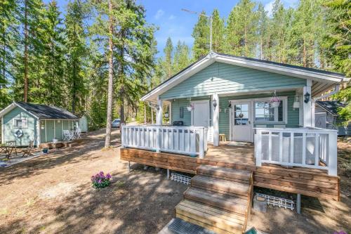 a small green cottage with a porch and a deck at Loistava Aurinkoranta Mökki in Ähtäri