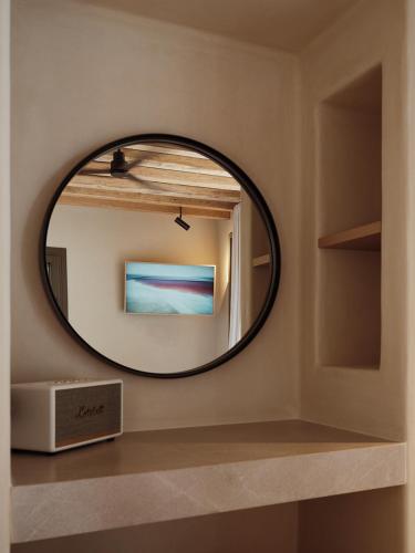a round mirror on a shelf in a room at NOS Hotel & Villas in Sifnos