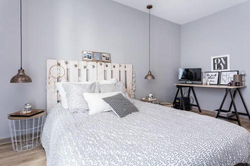 um quarto com uma cama grande e um edredão branco em Appartement Le Patio - Stationnement privatif & Tram - proche Montpellier em Saint-Jean-de-Védas