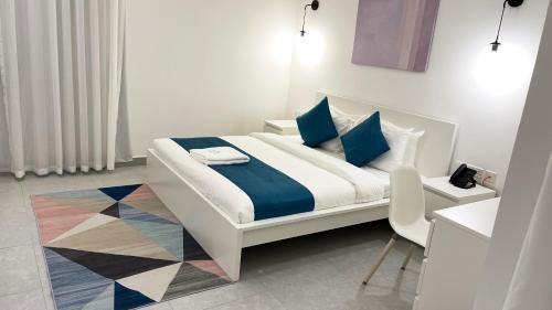 uma cama branca com almofadas azuis e uma cadeira num quarto em Terminal Inn By Edar City Centre em Doha