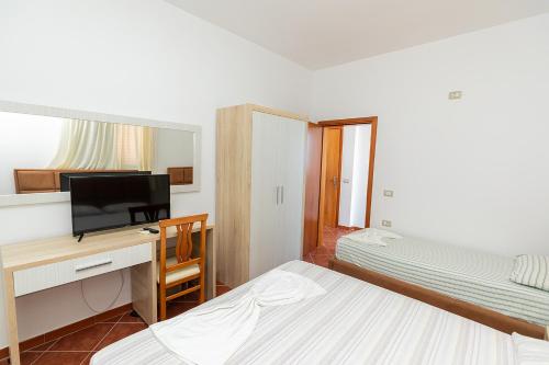 a bedroom with two beds and a desk and a mirror at Hotel Dini in Vlorë
