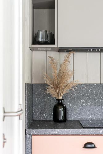 a black vase with a plant on a kitchen counter at SOPRANO - 'Virš Ąžuolų' - Forest SPA - FREE jacuzzi in Paplatelė