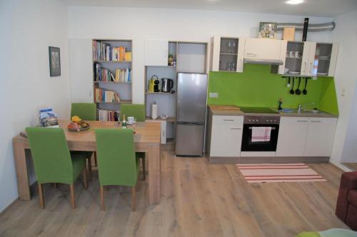 una cucina con tavolo in legno e sedie verdi di Elli, Appartement inklusive kostenfreiem Eintritt in die Alpentherme a Bad Hofgastein