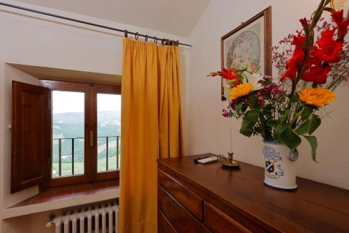 a vase of flowers on a dresser with a window at Relais Vignale & Spa in Radda in Chianti