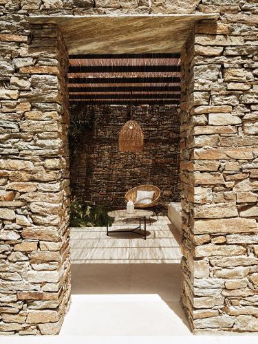 a stone walled patio with a table and a chair at NOS Hotel & Villas in Sifnos