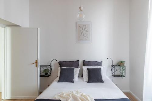 um quarto com uma cama branca e almofadas cinzentas em iFlat Colosseo Modern Apartment em Rudiano