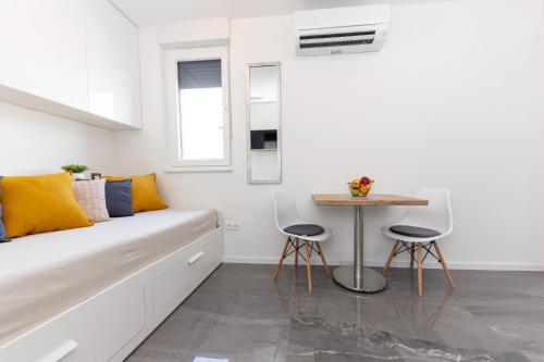 ein weißes Zimmer mit einer Bank und einem Tisch in der Unterkunft Cozy new studio SHOOKA - SPLIT in Split