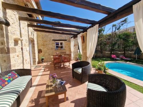 a patio with a couch and chairs next to a pool at Rock House's Villa Melody in Plataniás