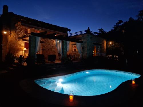 a swimming pool in front of a house at night at Rock House's Villa Melody in Plataniás