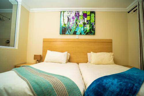 a bedroom with two beds and a painting on the wall at 17 on 13th in Edenvale