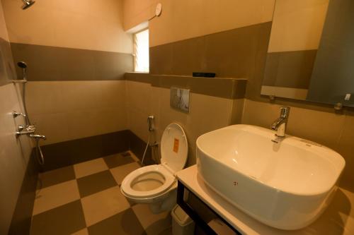 a bathroom with a white toilet and a sink at Coastal Pearl Hotel Miramar Panaji in Panaji